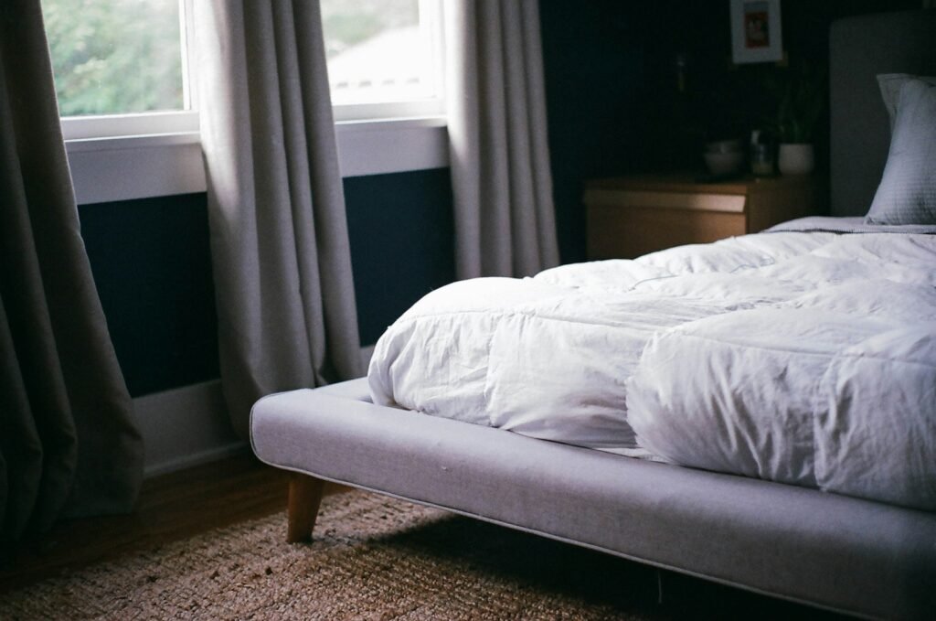 Weißes Bett am Fenster bei Tageslicht – Matratze nach dem Reinigen gut lüften