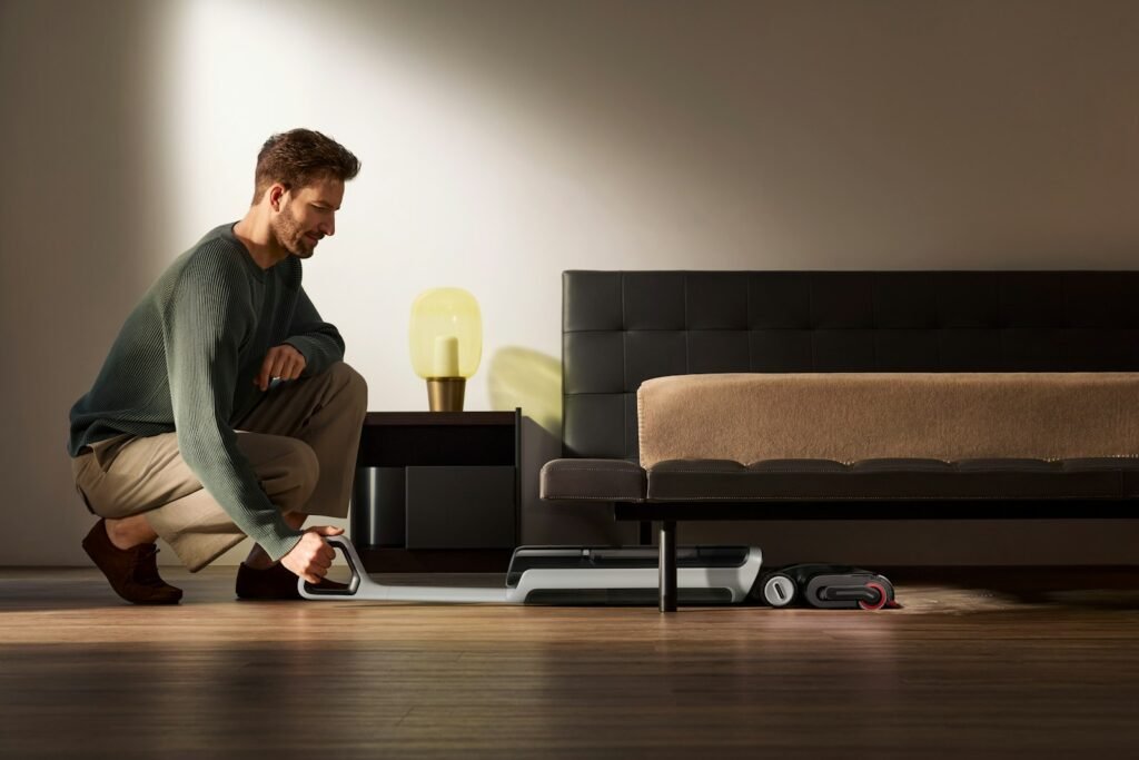 Mann saugt unter dem Bett – Matratze reinigen beginnt mit gründlichem Staubsaugen