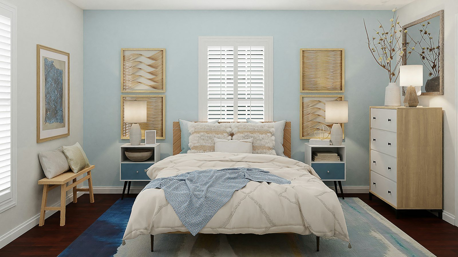 The bedroom has a calming and modern design with a predominantly light blue color scheme. The bed is centrally placed with a white comforter and a blue textured throw blanket. Matching blue side tables with lamps flank each side of the bed. A dresser stands on the right, adorned with decorative branches in a vase and a table lamp. Textured wall art and framed abstract paintings add to the decor. Wooden elements and soft cushions provide warmth, and there is ample natural light coming through the window blinds.